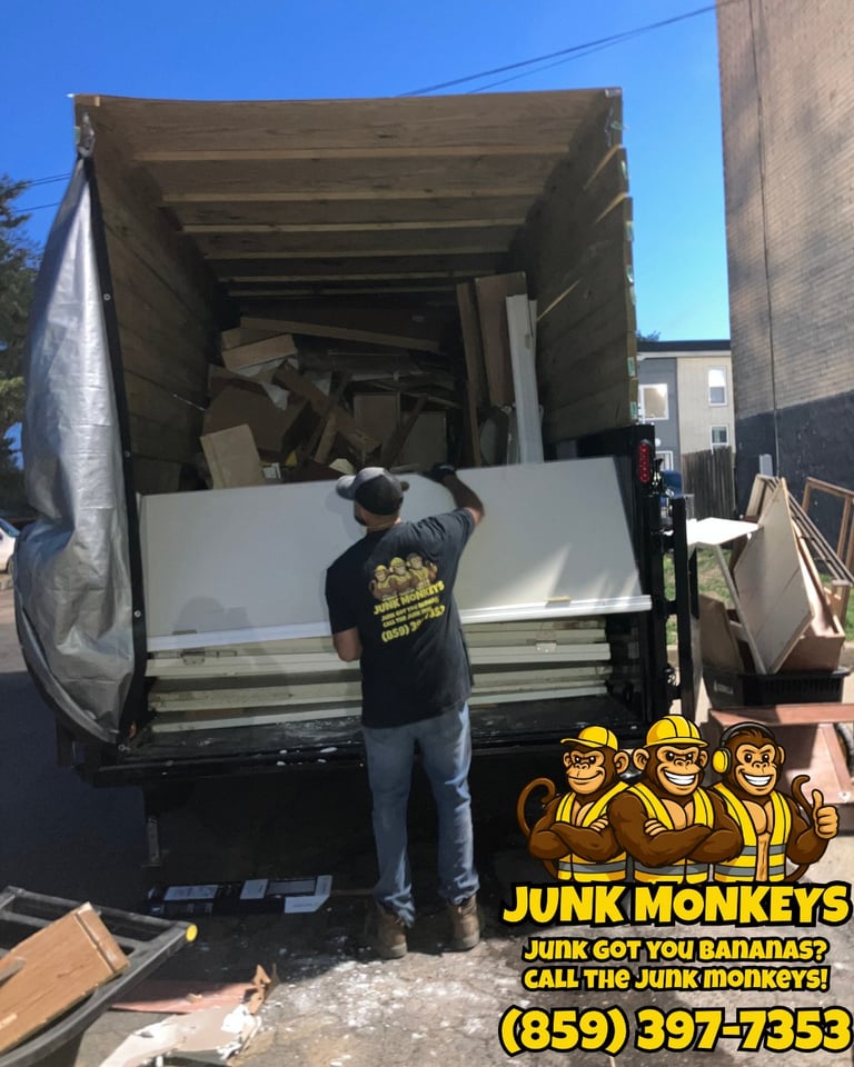 Worker loading junk into open moving truck with Junk Monkeys logo and phone number displayed